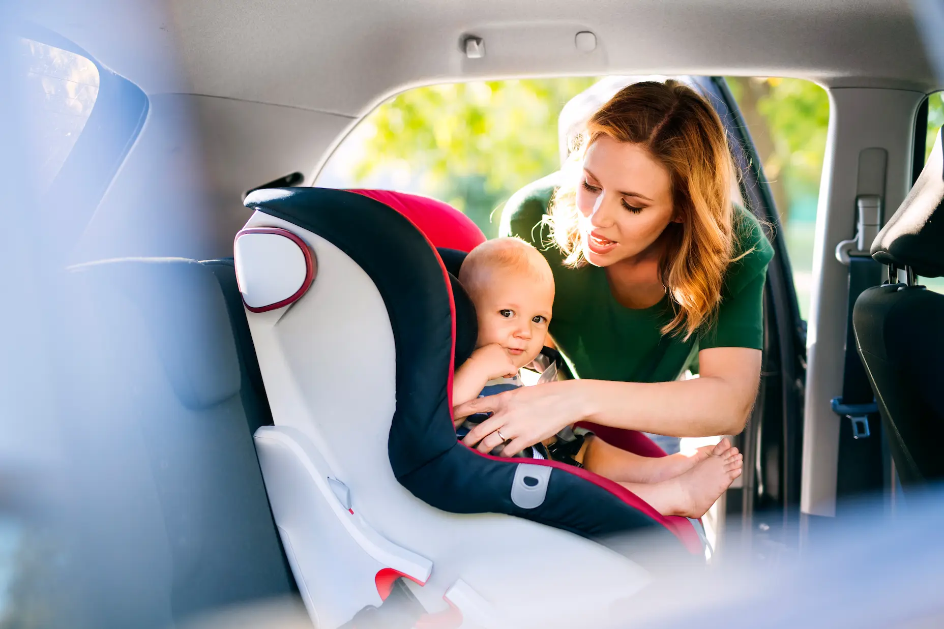 Mother securing a baby in a car seat